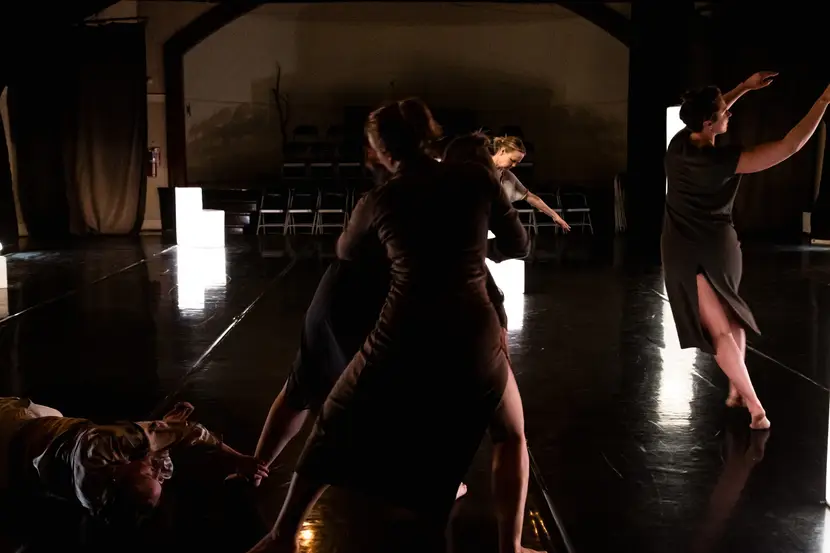 In a shadowy dance studio, people are caught by the camera halfway between dancing and falling